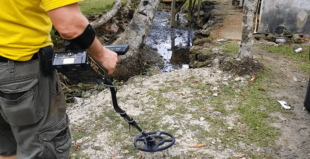 Person using a metal detector near a stream.